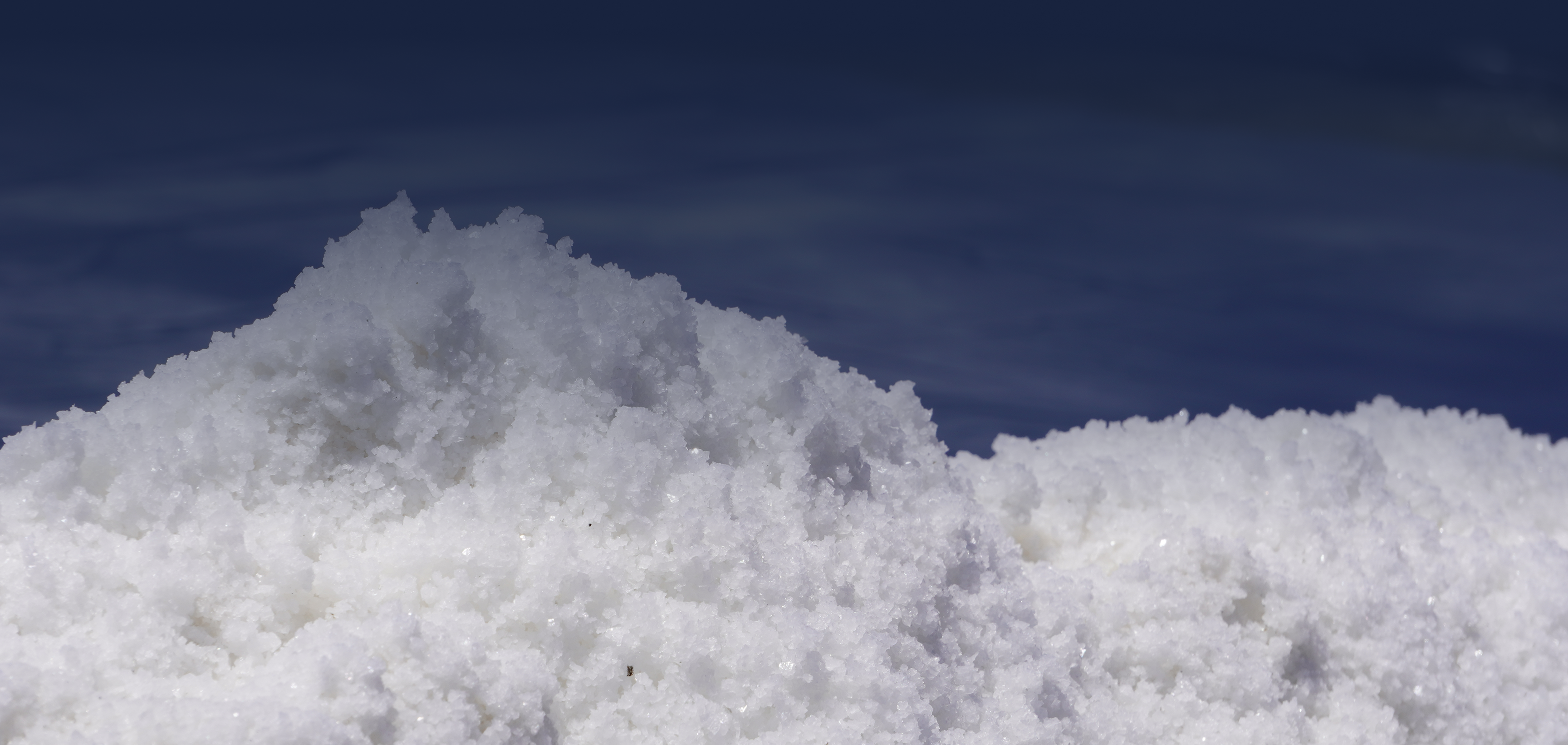 Large pile of white salt crystals against a dark blue sky